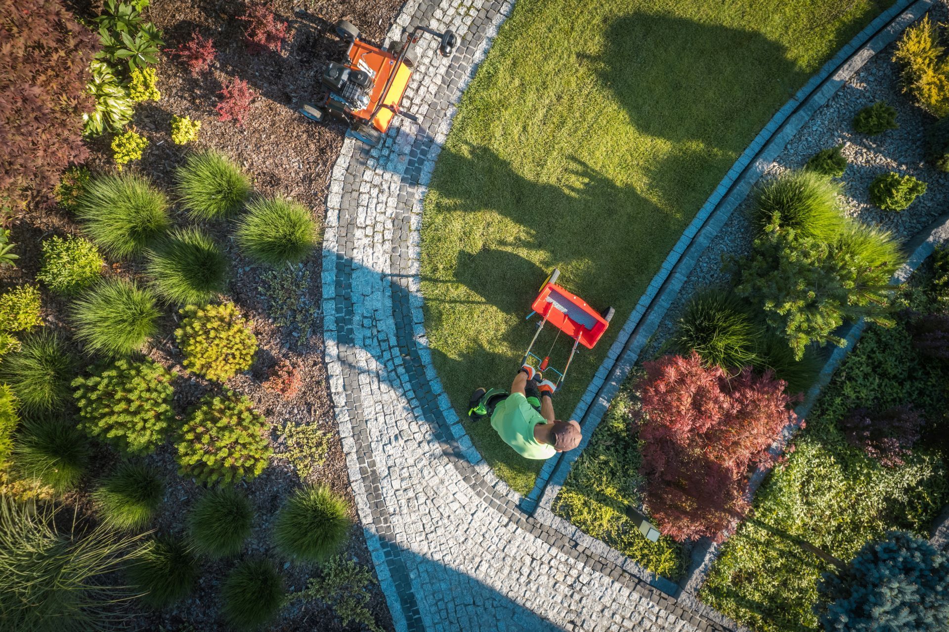 An aerial view of a man mowing a lawn with a lawn mower.