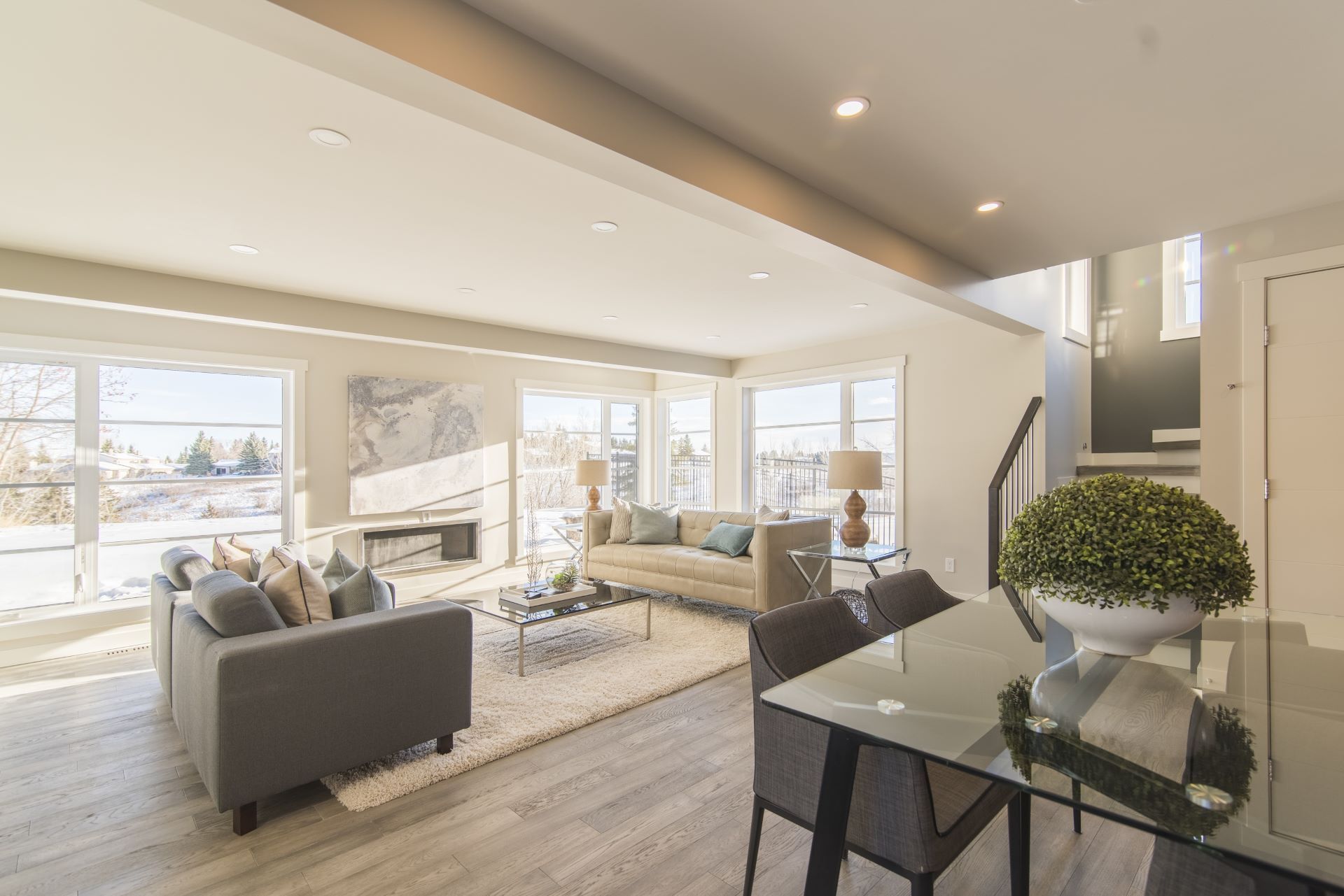 A living room and dining room in a house with a glass table and chairs.
