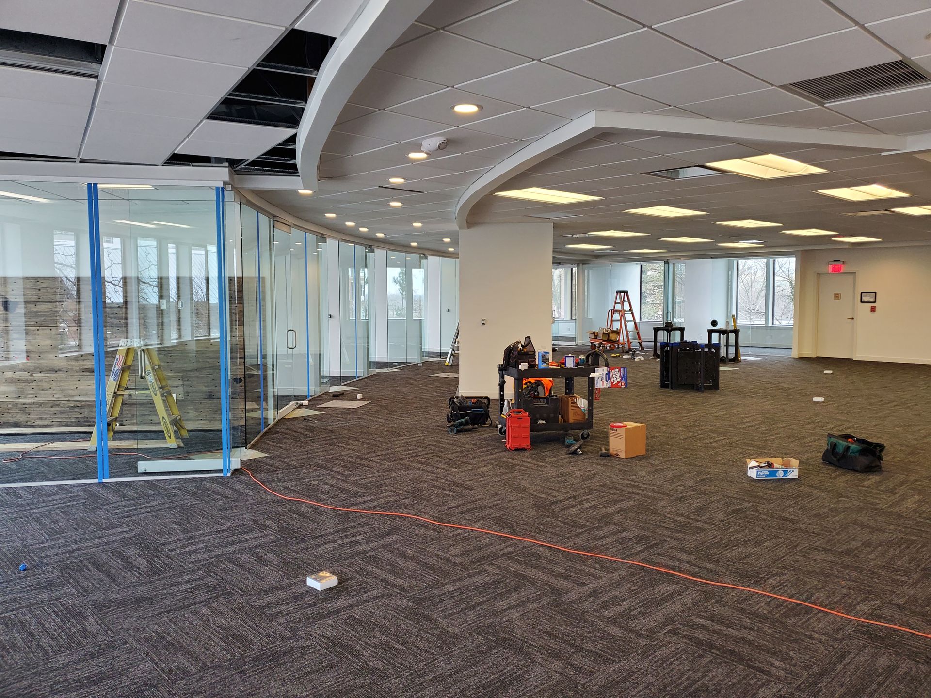 A large empty room with a lot of windows and boxes on the floor.