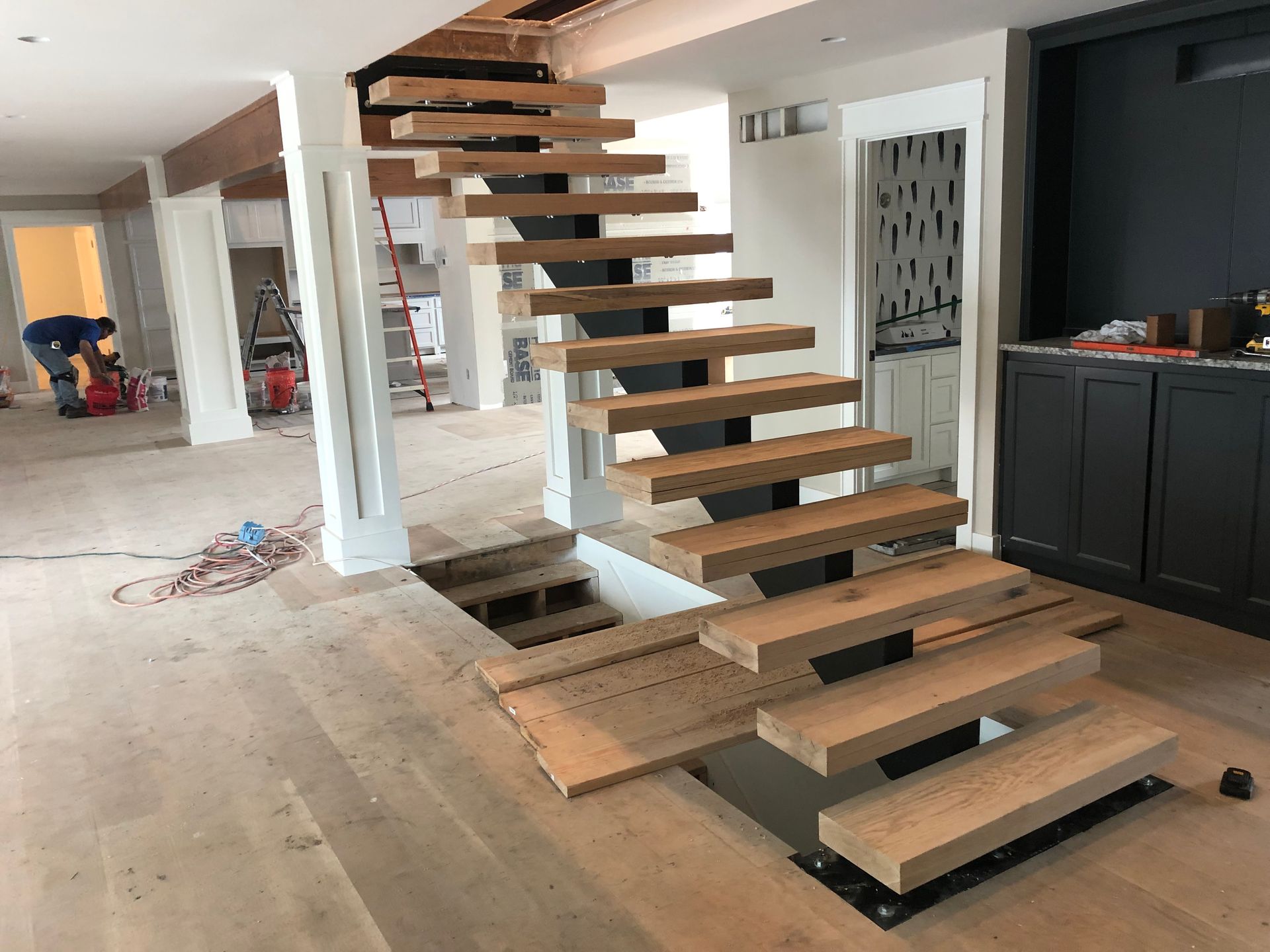 A wooden staircase is being built in a living room.