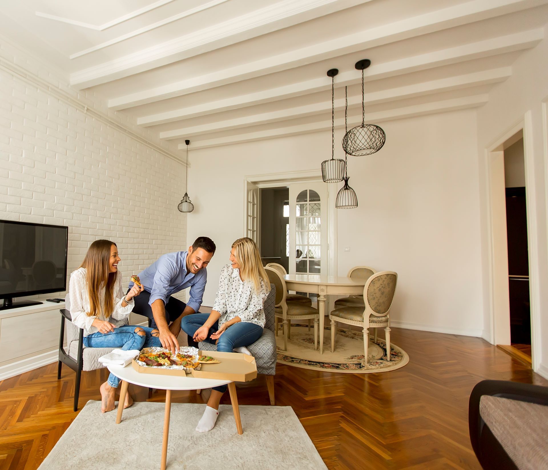 A group of people are sitting around a table in a living room.