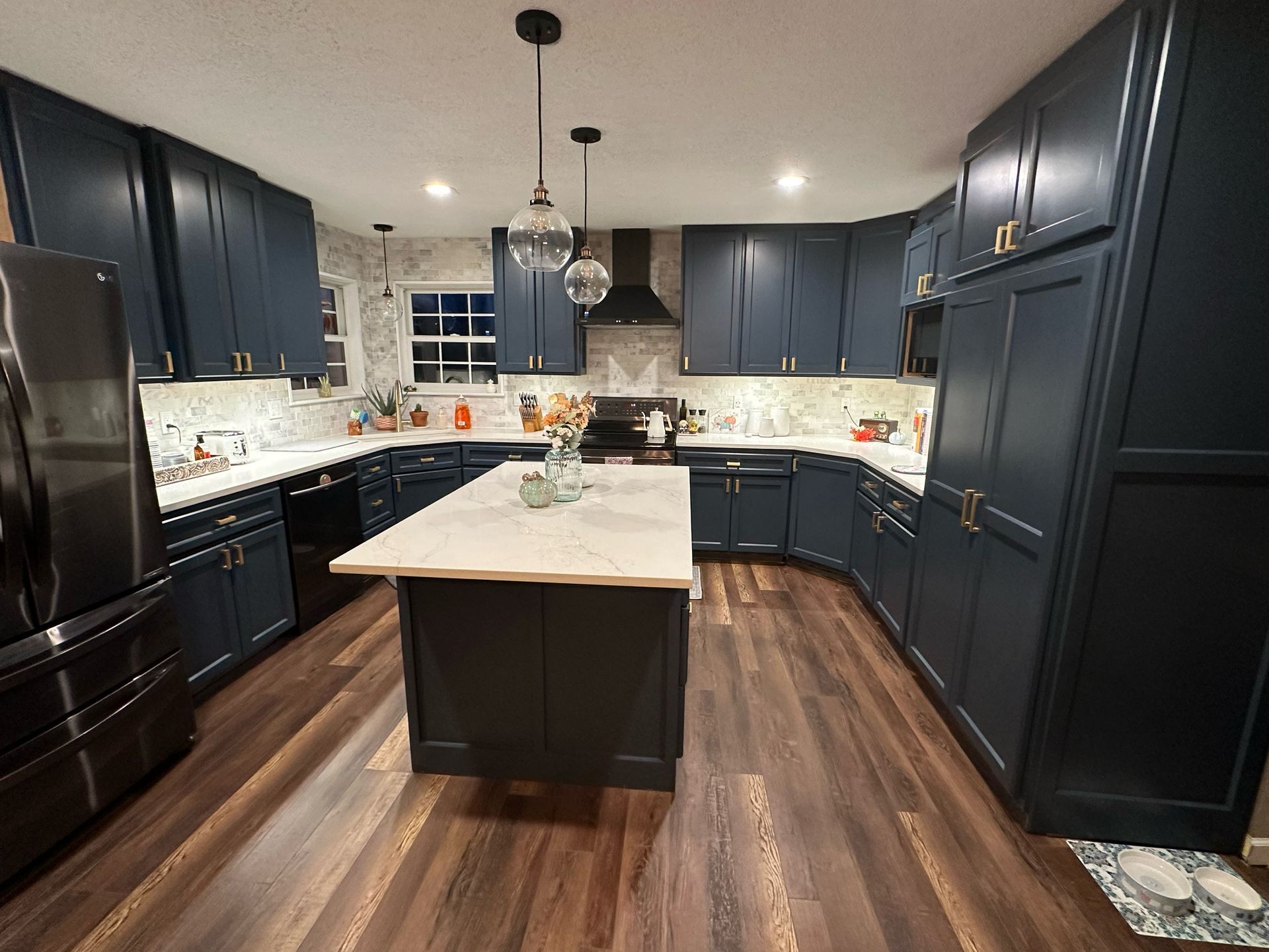 A kitchen with blue cabinets and a large island in the middle.
