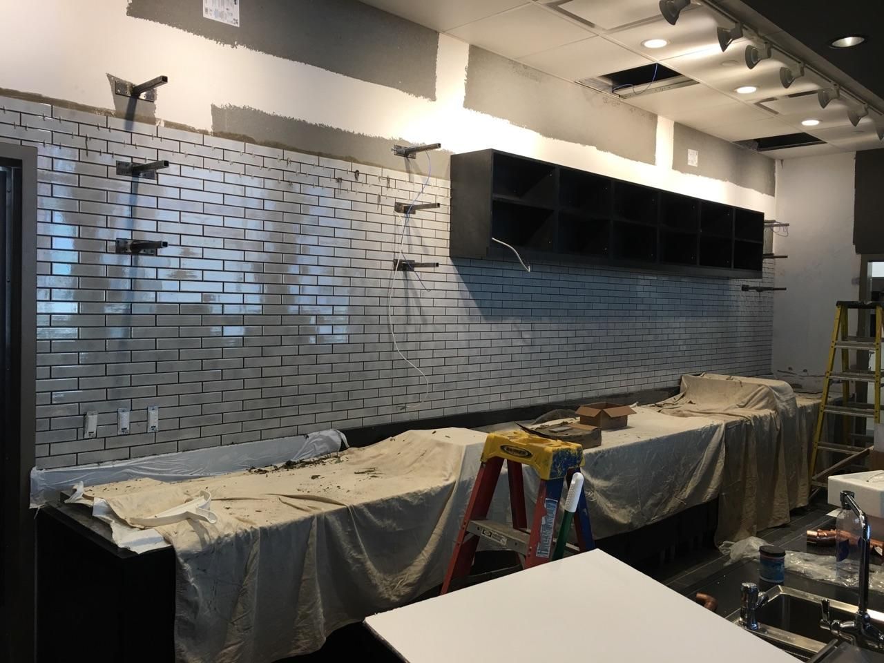 A kitchen is being remodeled with a brick wall and a ladder.