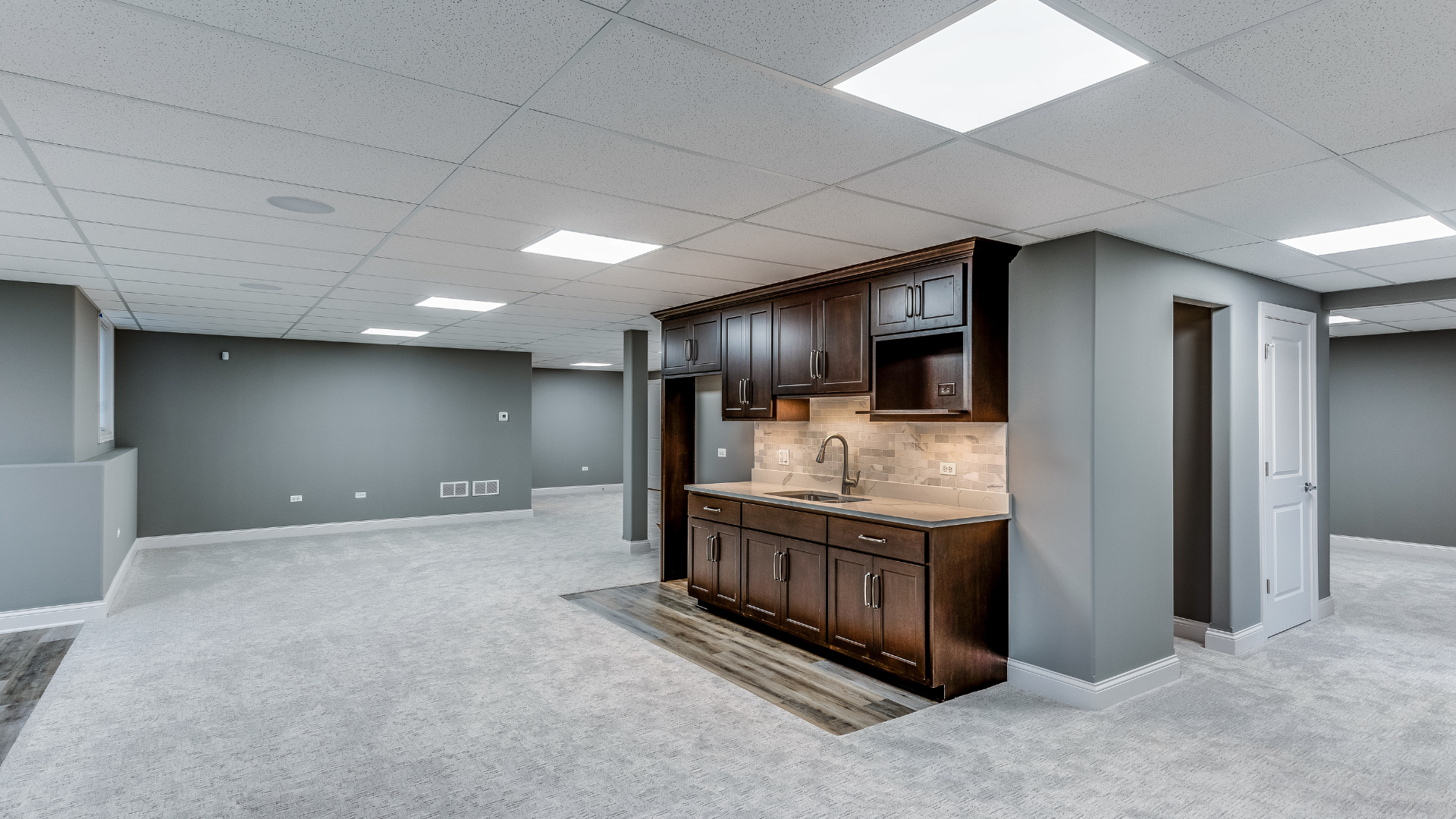 There is a kitchen in the basement with a sink and cabinets.
