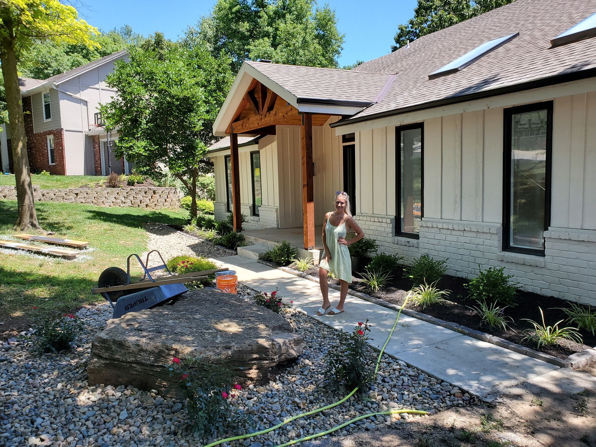 A woman is standing in front of a white house.