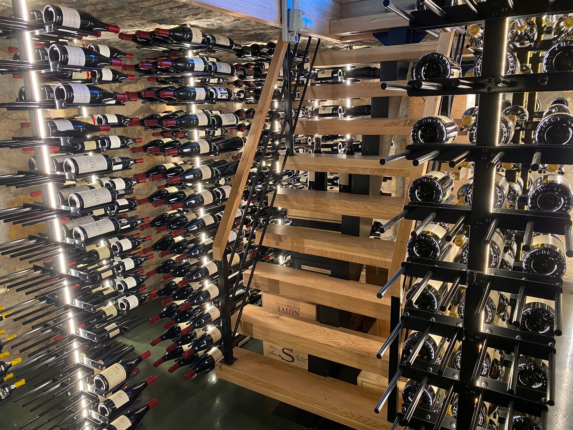 A wine cellar filled with lots of bottles of wine and stairs.