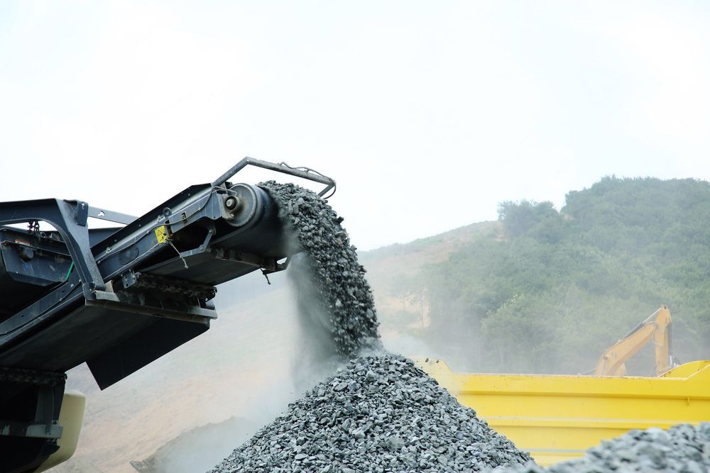 A Pile Of Rocks Is Being Poured Into A Yellow Dumpster — Ian Brown Sand Supplies and Tipper Hire In Laurieton, NSW