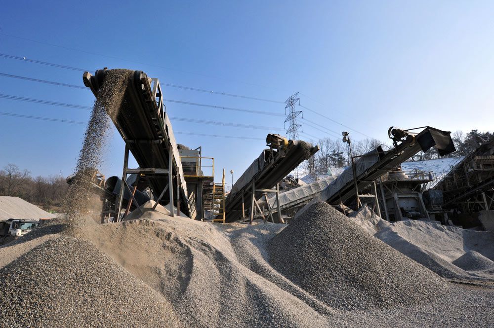 A Pile Of Gravel Is Being Poured From A Conveyor Belt Into A Pile Of Gravel — Ian Brown Sand Supplies and Tipper Hire In Port Macquarie, NSW