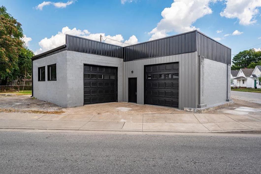 A garage with two garage doors is sitting on the corner of a street.