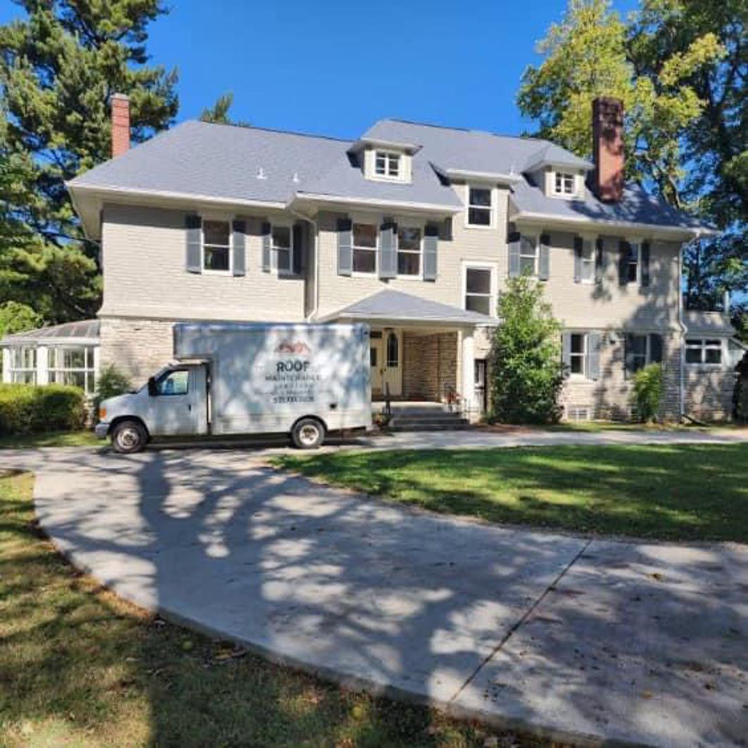 A white truck is parked in front of a large house