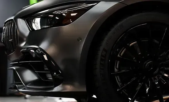 Matte gray sports car, black wheel, and headlight detail.