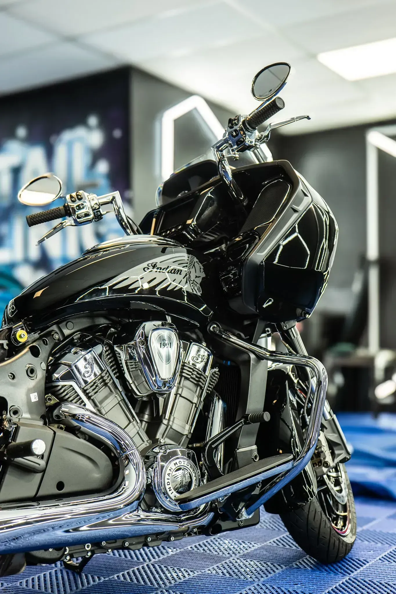 Shiny black motorcycle with chrome engine, in a shop setting.