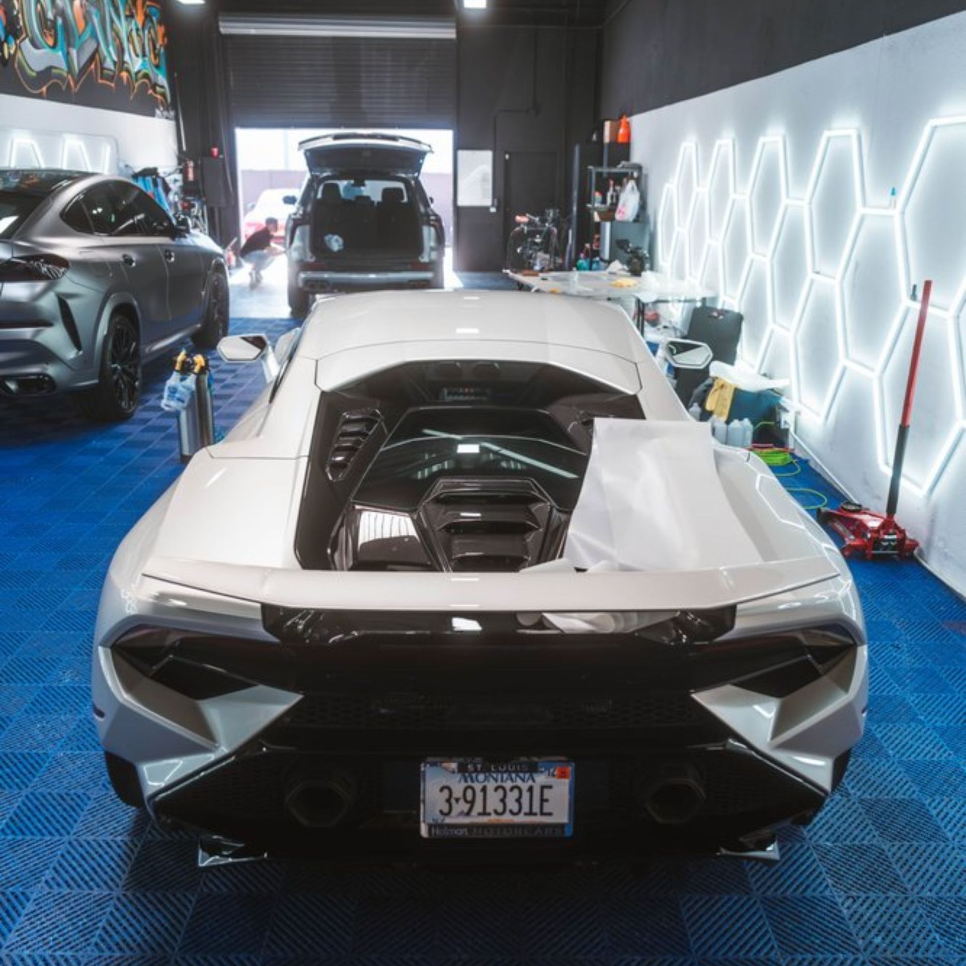 White Lamborghini in a garage with other vehicles.