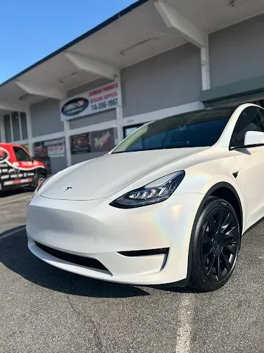 Black car being polished, worker's hands, close-up, shiny paint, checkered floor.