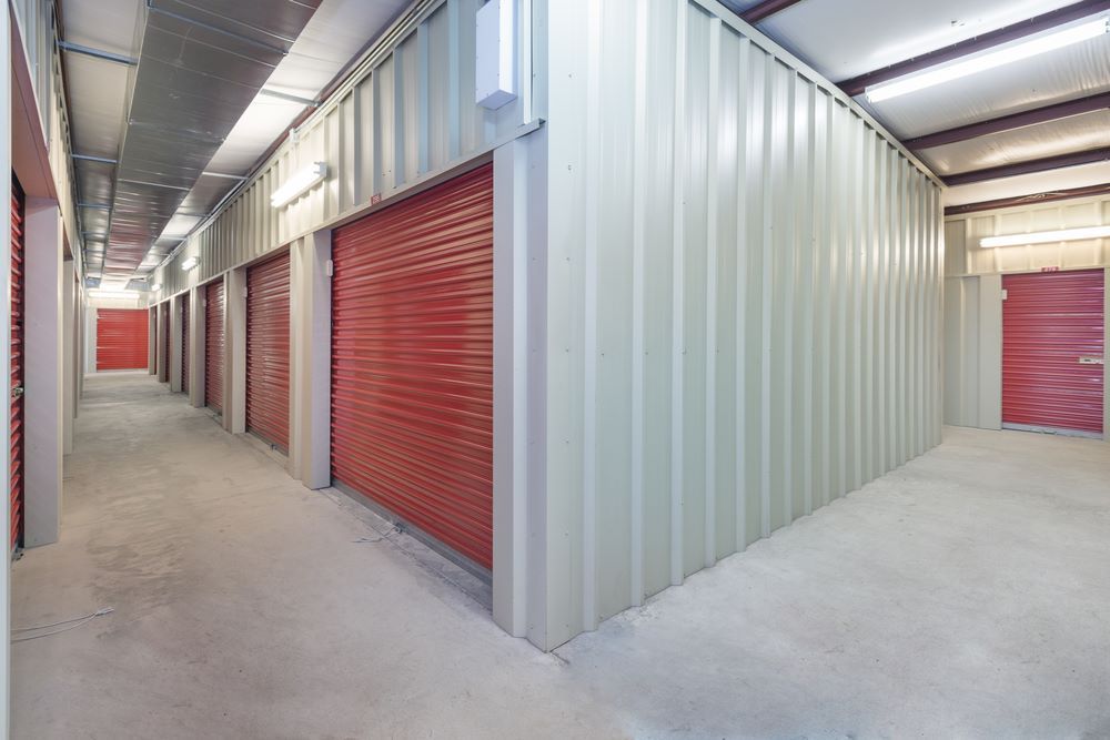 A Long Hallway in a Storage Facility With Red Doors — Kingaroy Self Storage Sheds in Kingaroy, QLD