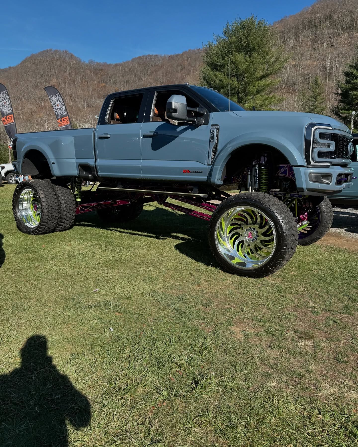 Close-up of a white truck wheel with a black tire and rim. The tire is dirty with mud.