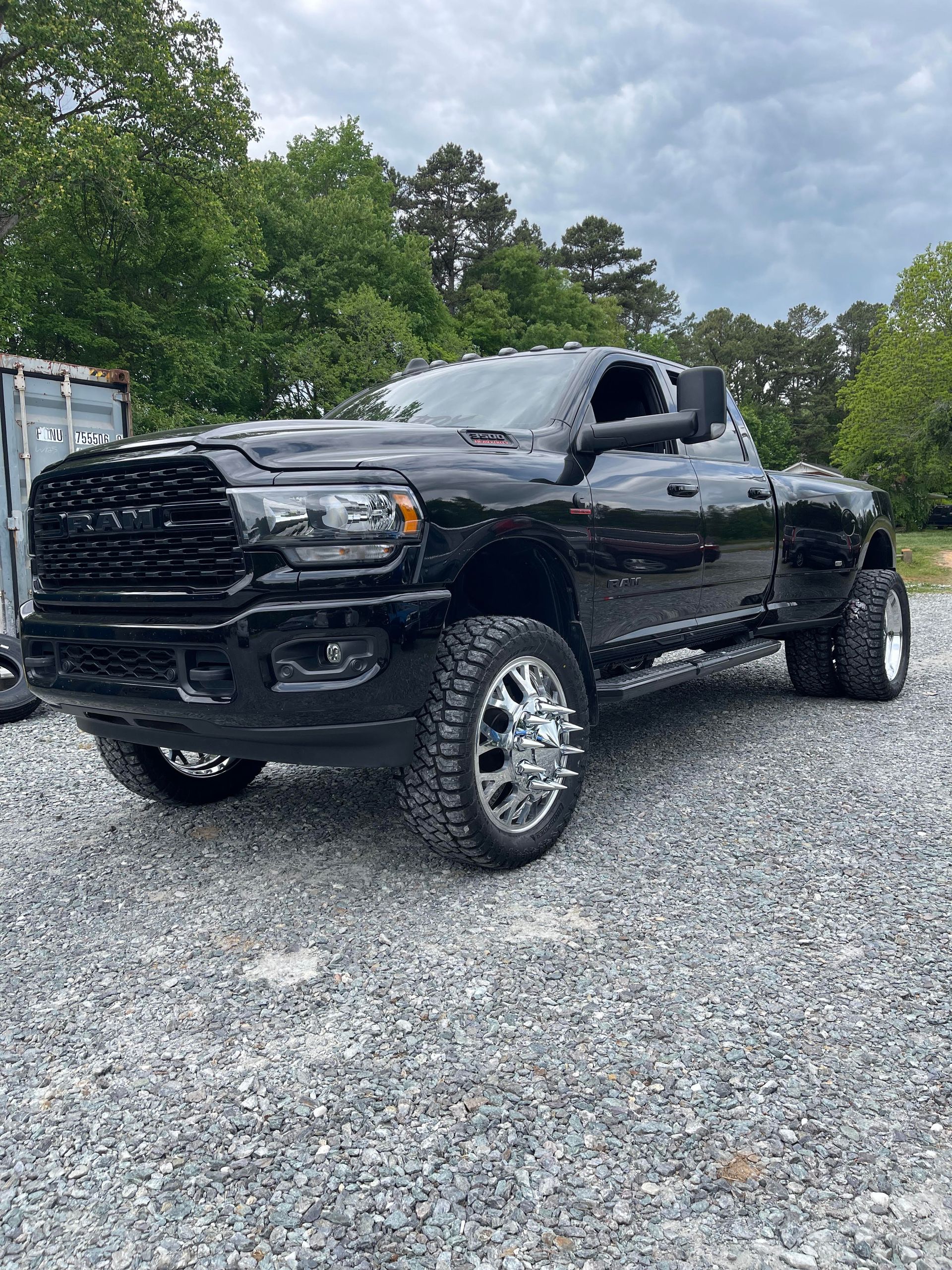Red car on a lift in a garage; wheels removed.