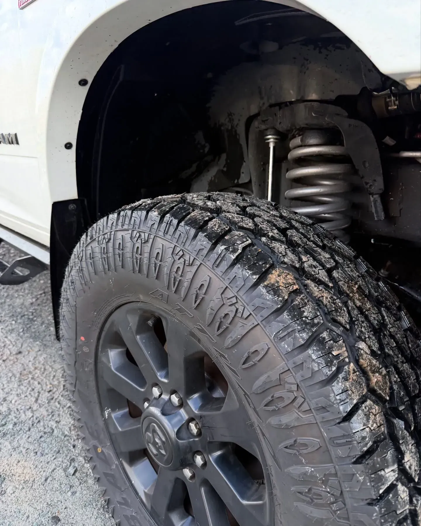 A silver car wheel on a blue tire machine in a garage.