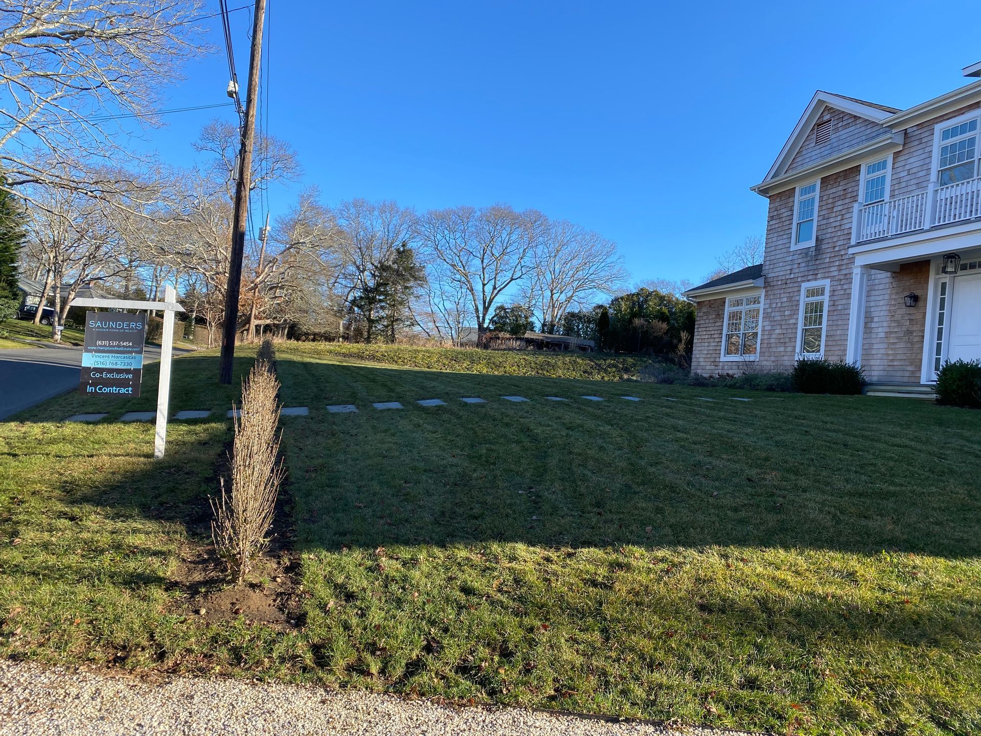 A house with a lot of grass and a for sale sign in front of it.