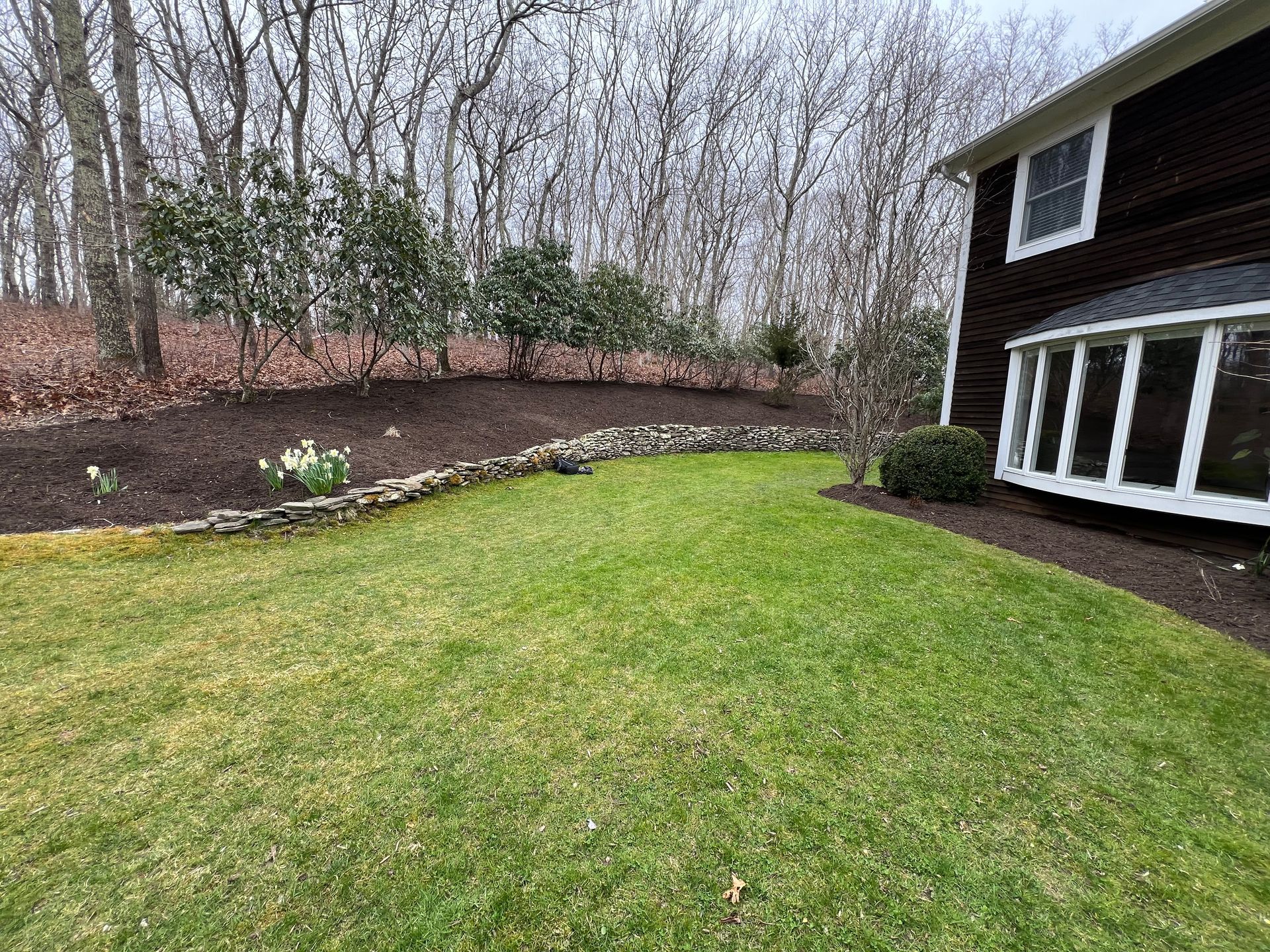 A large lawn in front of a house with trees in the background.