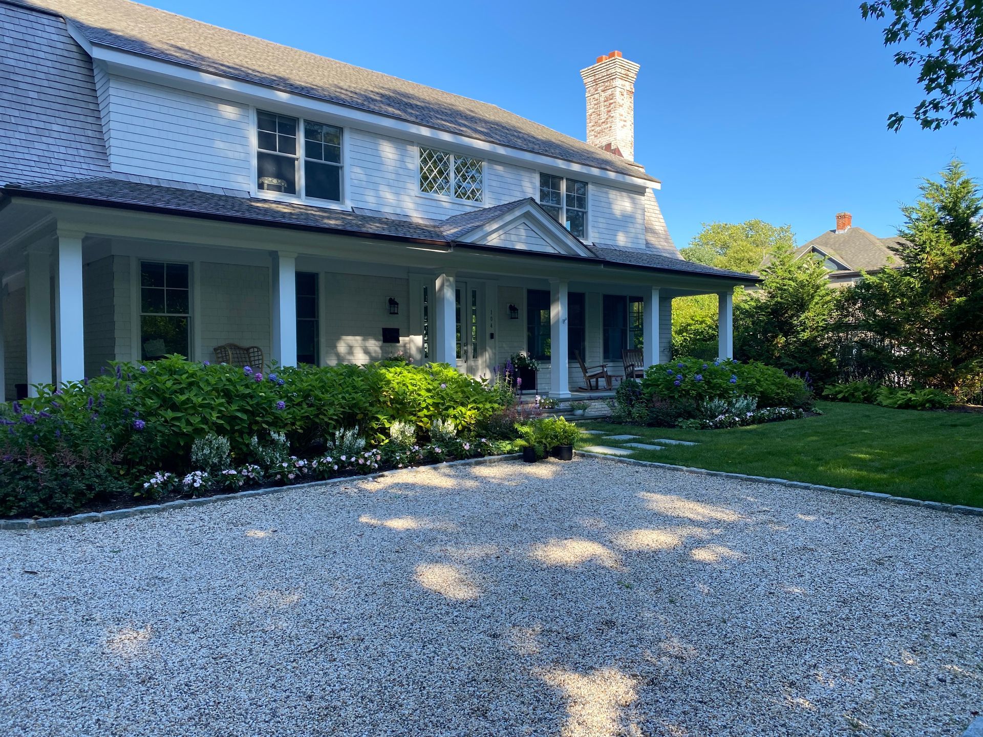 A large white house with a gravel driveway in front of it.