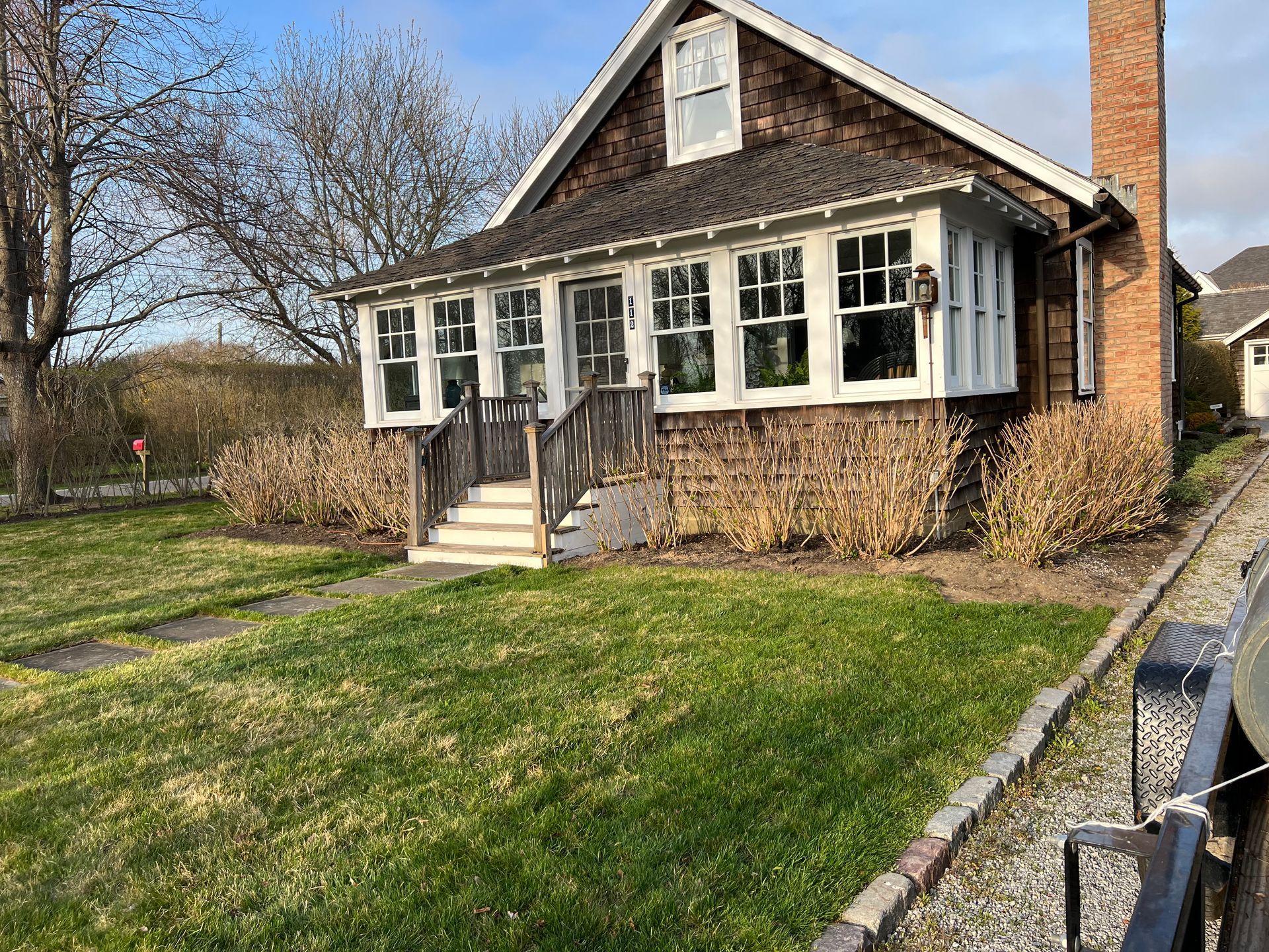 A house with a lot of windows and a large lawn in front of it.