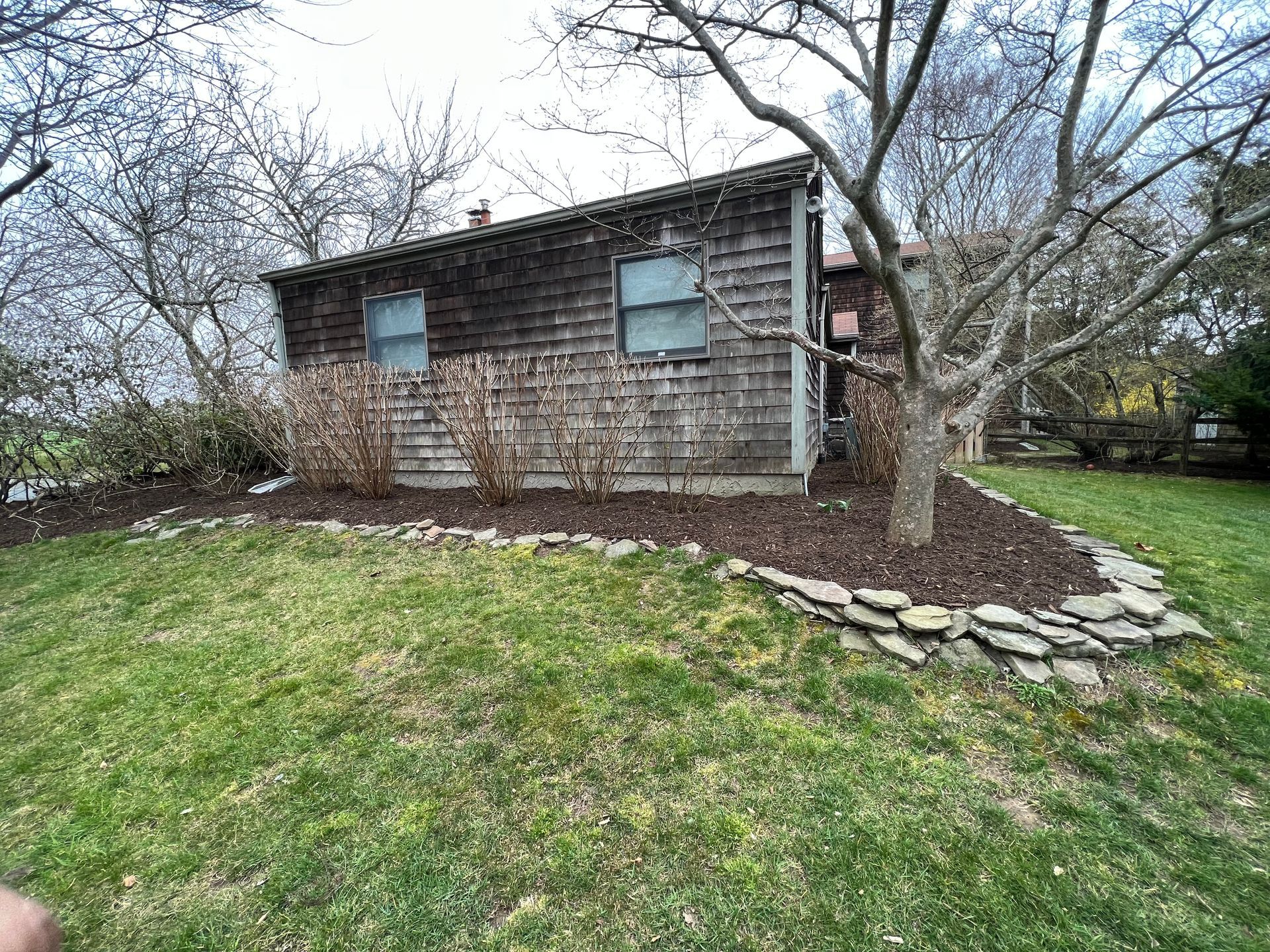 A small house is sitting in the middle of a lush green field.