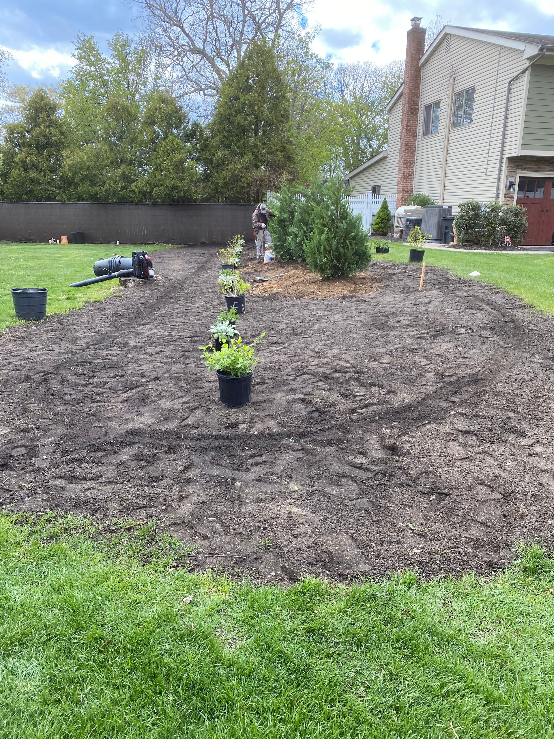 A man is planting plants in a garden in front of a house.