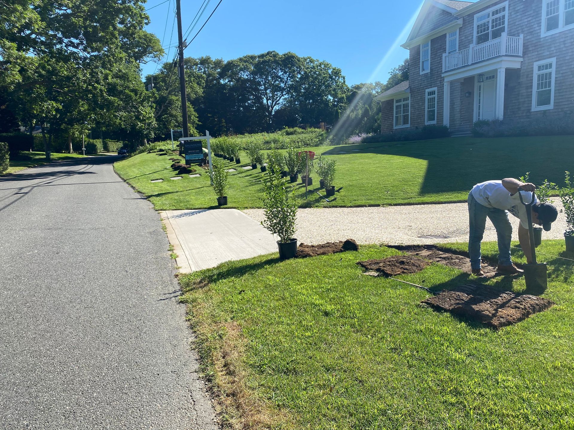 A man is planting trees in front of a house