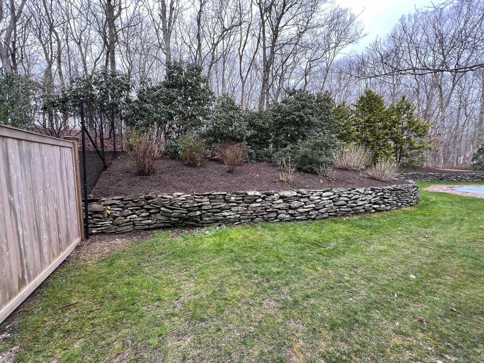 There is a stone wall in the middle of the yard.
