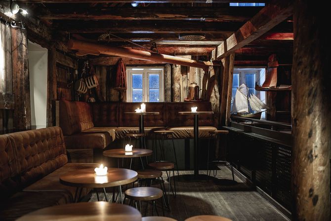 A dark room with tables and stools with candles on them