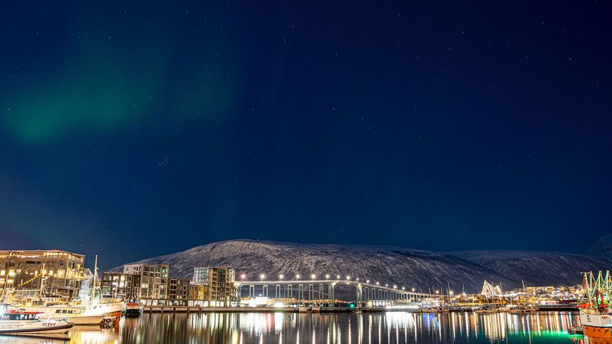 The aurora borealis is visible over Tromsø city at night