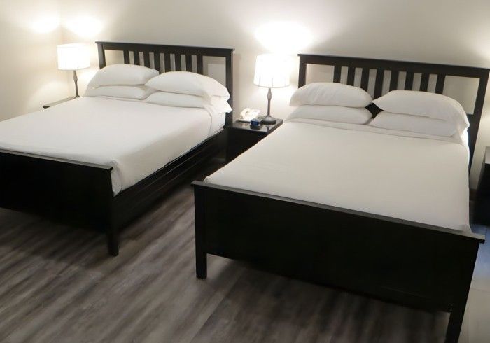 Two beds in a hotel room with white sheets and pillows