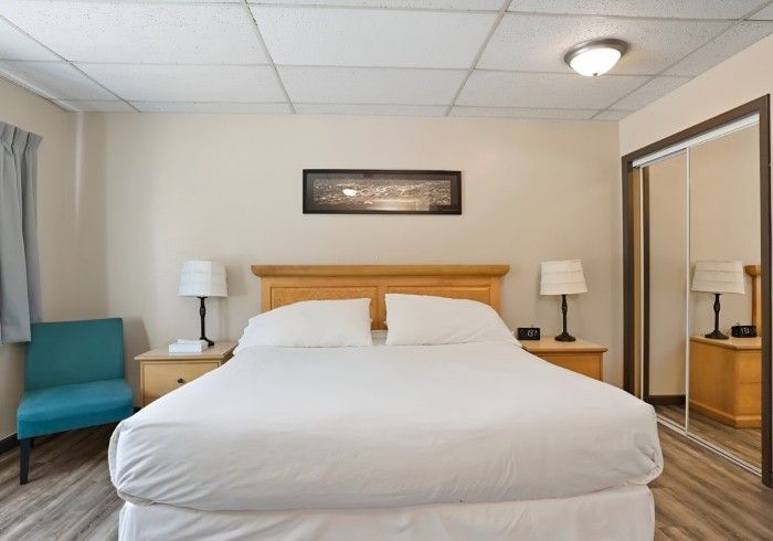 A hotel room with a king size bed and a chair