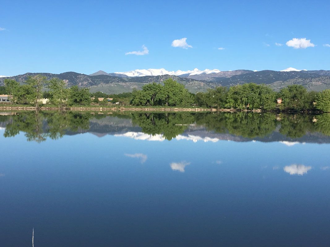 A lake with mountains in the background and trees in the foreground
