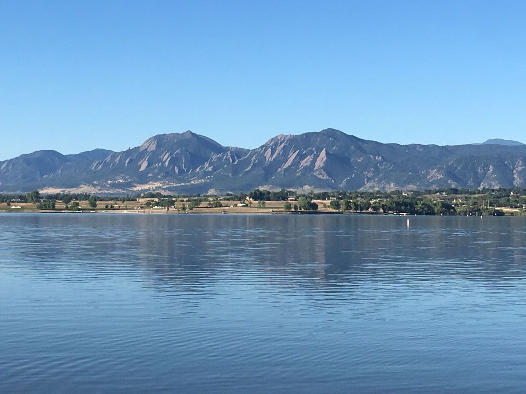 A lake with mountains in the background and trees on the shore.