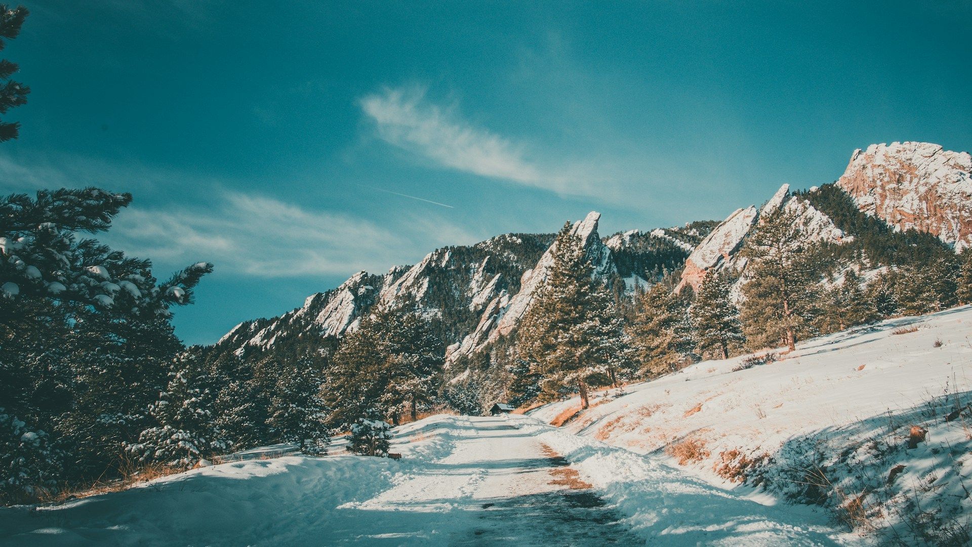 A snowy road leading to a mountain covered in snow.