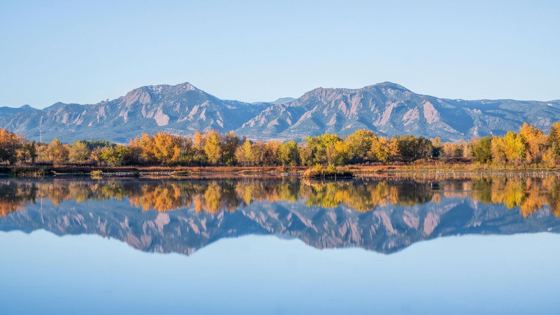 A lake with mountains in the background and trees reflected in the water.