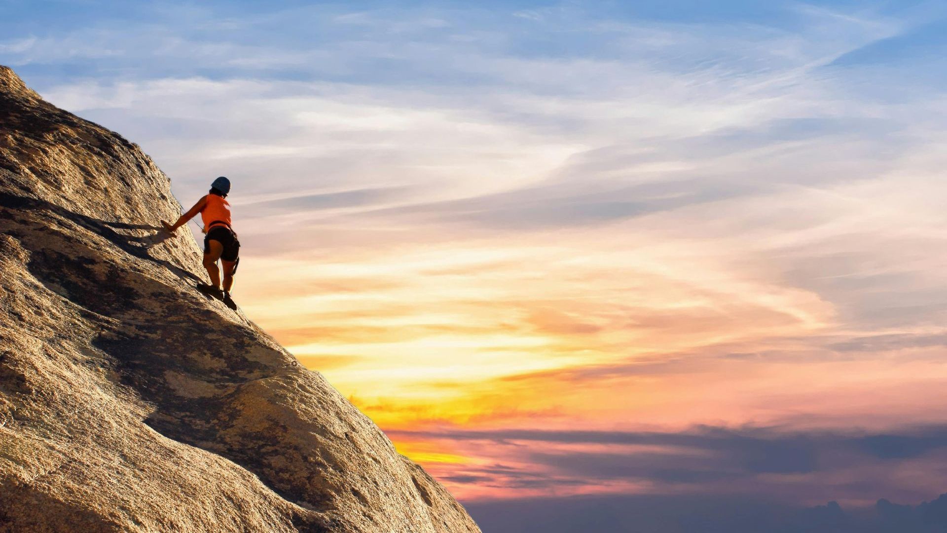 A person is climbing a mountain at sunset.