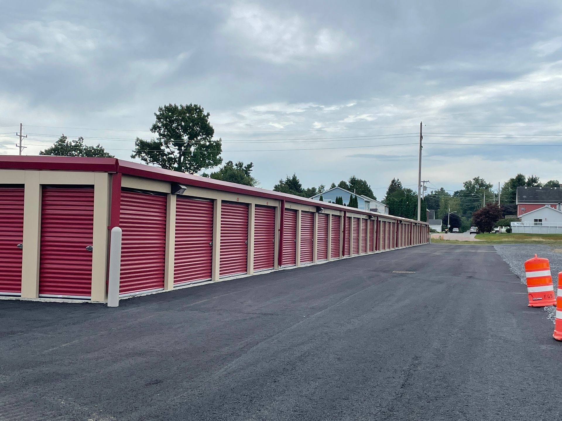 A row of red storage units are lined up in a parking lot.