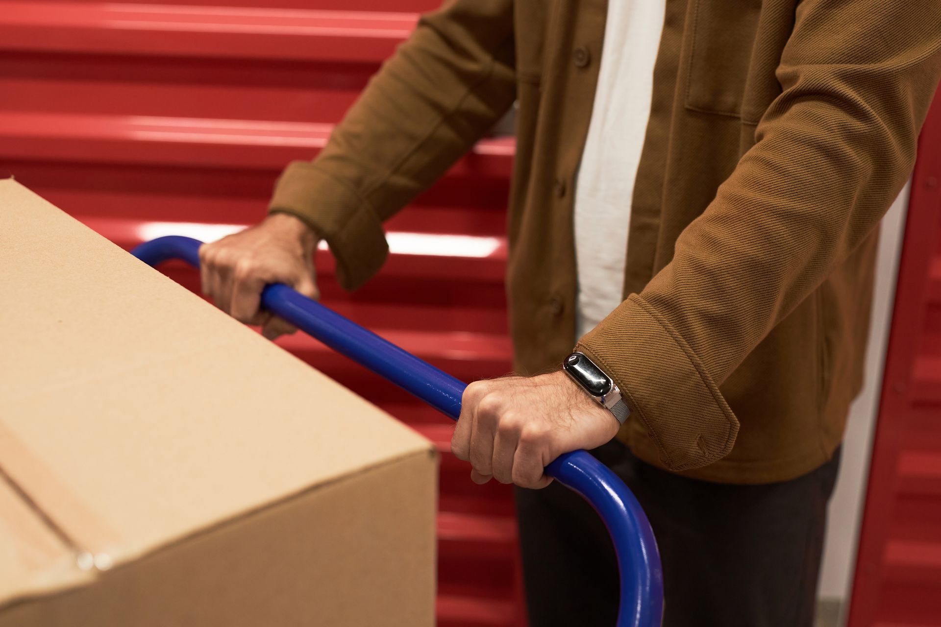 A man is pushing a cart with a cardboard box on it.