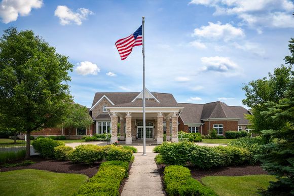A brick building with a portico and a central American flag under a bright blue sky with light clouds.