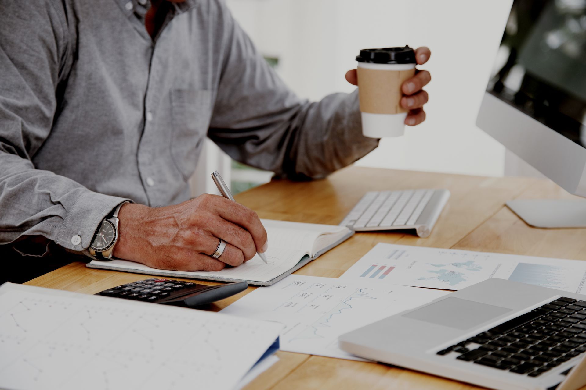 A man is sitting at a desk holding a cup of coffee.