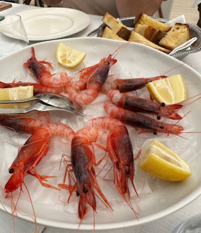 Un piatto bianco condito con gamberi e fette di limone