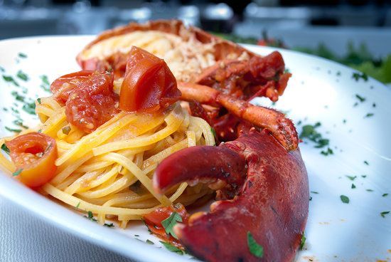 Un piatto bianco condito con spaghetti e un'aragosta