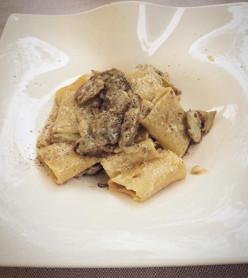 Un piatto bianco condito con pasta e funghi