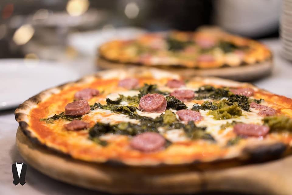 Un primo piano di una pizza su un tagliere di legno.