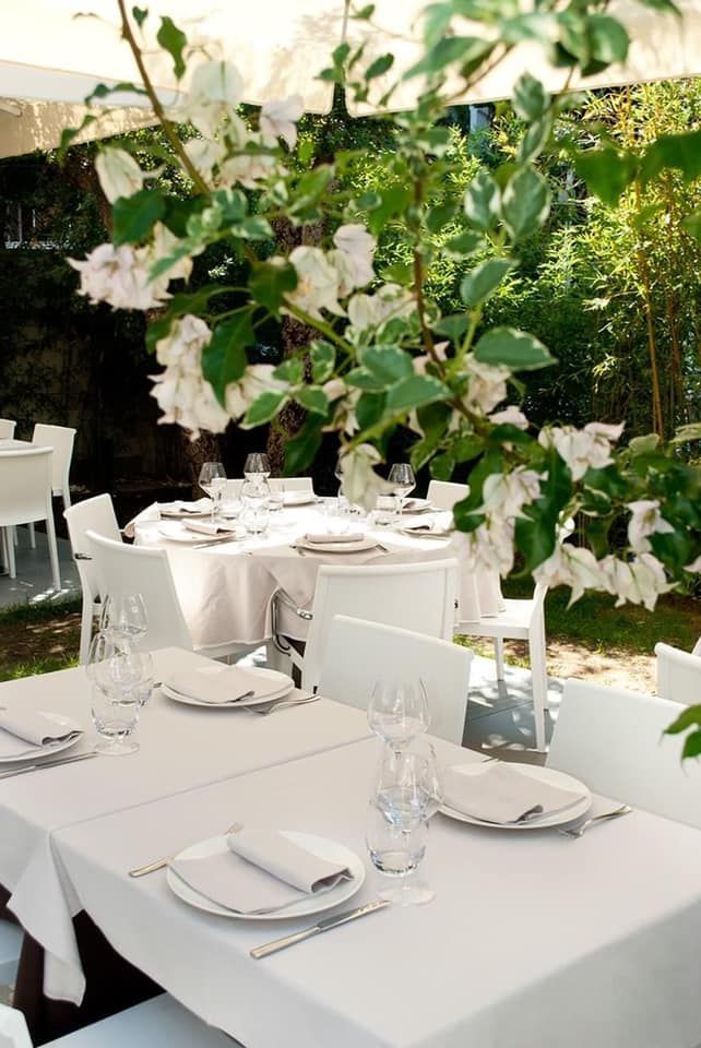 Un ristorante con tavoli e sedie bianchi e fiori sullo sfondo