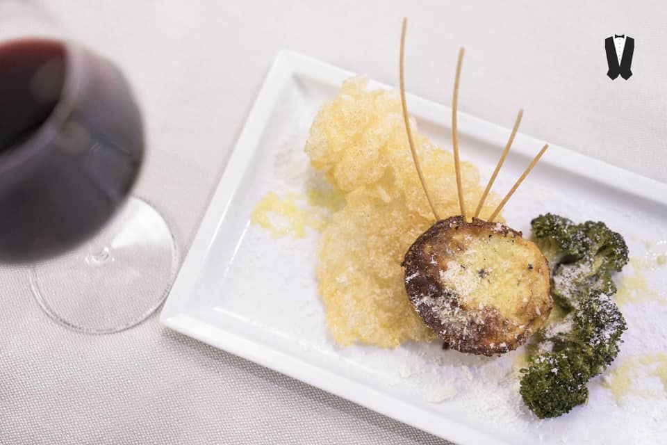 Un piatto di cibo e un bicchiere di vino su un tavolo.
