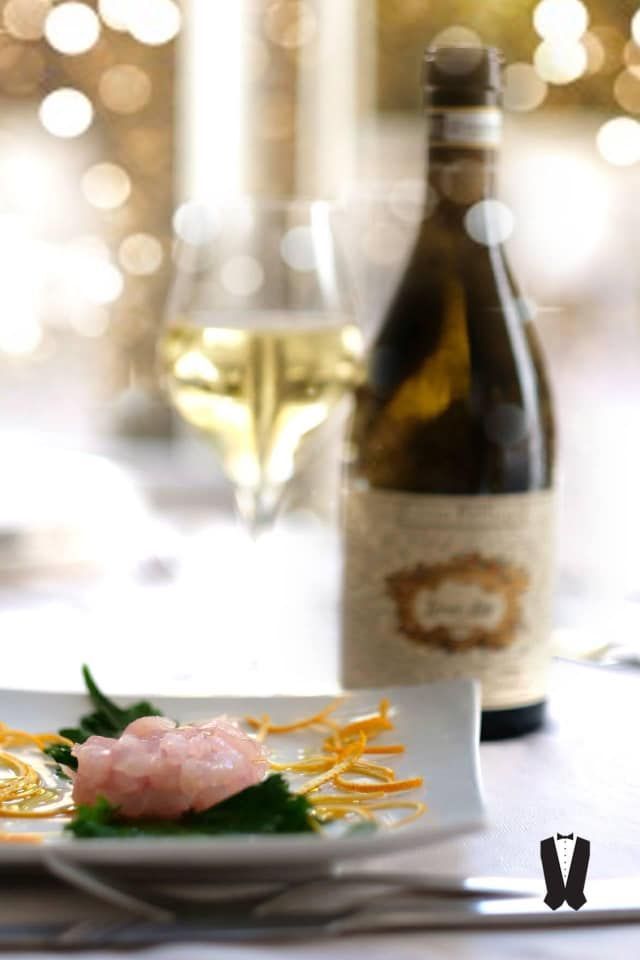 Una bottiglia di vino si trova accanto a un piatto di cibo su un tavolo.